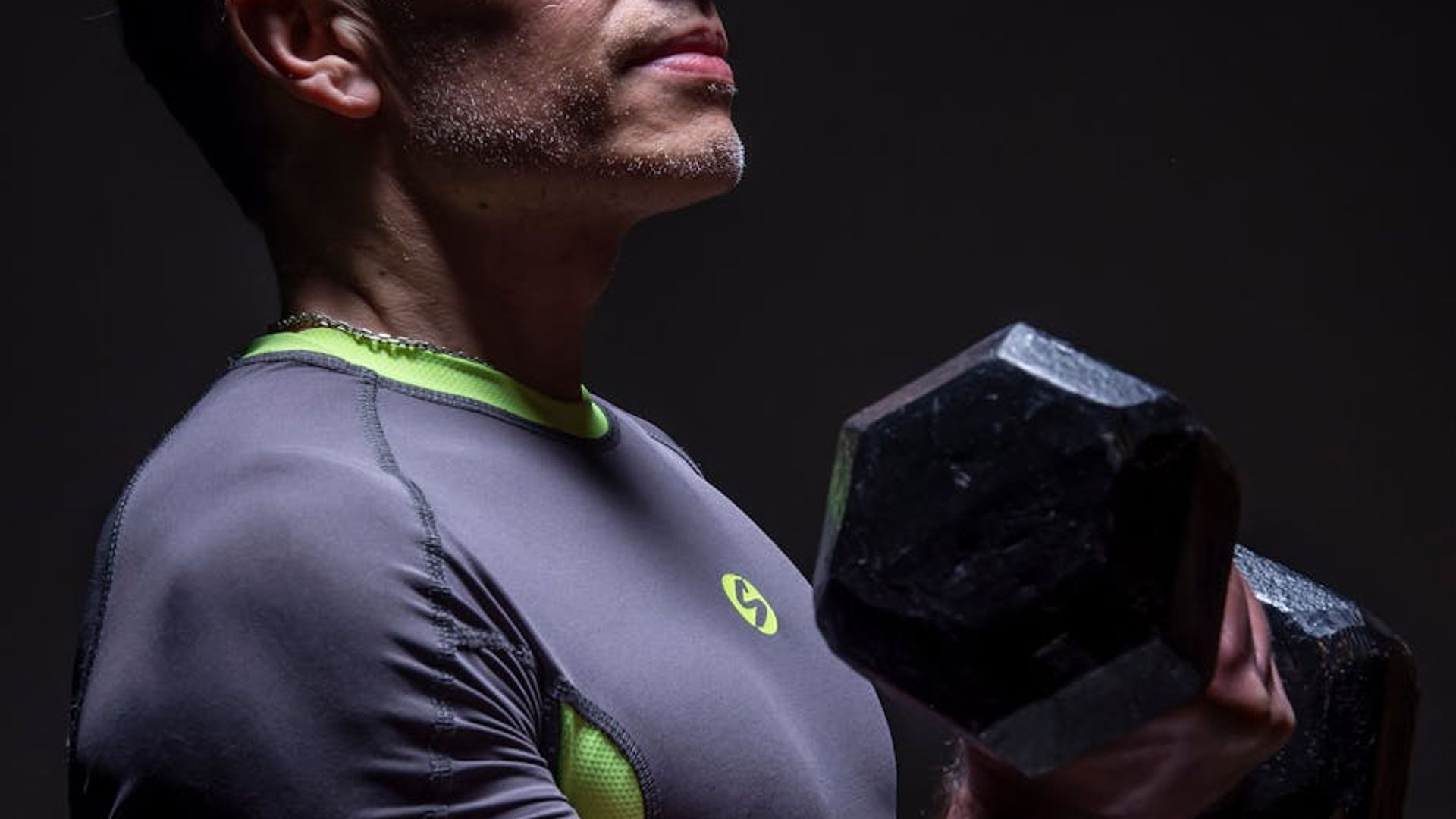Man focused during a strength exercise in a minimalist gym with dark tones.